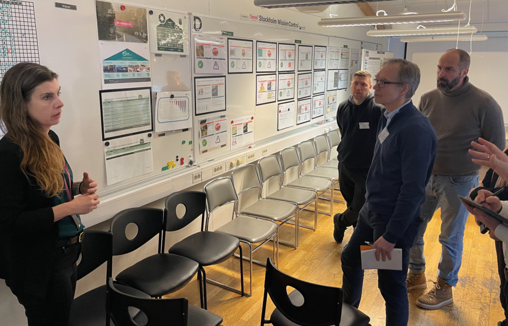 Team i forbedringsarbeid foran Lean-tavle som del av læring og dialog